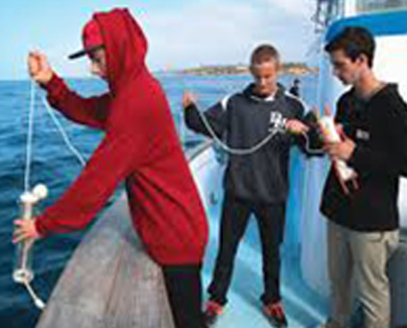 Three young boys participate in the marine science education program in Newport Beach.